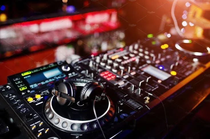 DJ mixing on a console at a party event with coloured lights